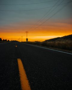 A road with a sunset in the background Description automatically generated with medium confidence